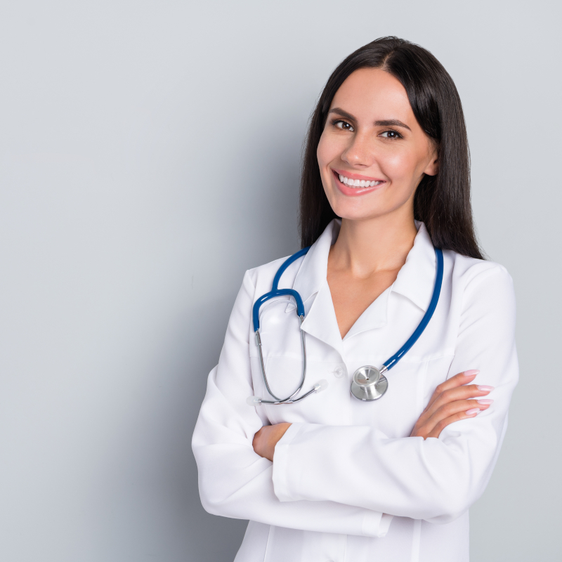 Portrait,Of,Pretty,Positive,Lady,Crossed,Hands,Empty,Space,Blank A smiling female doctor in a white lab coat with a stethoscope around her neck.
