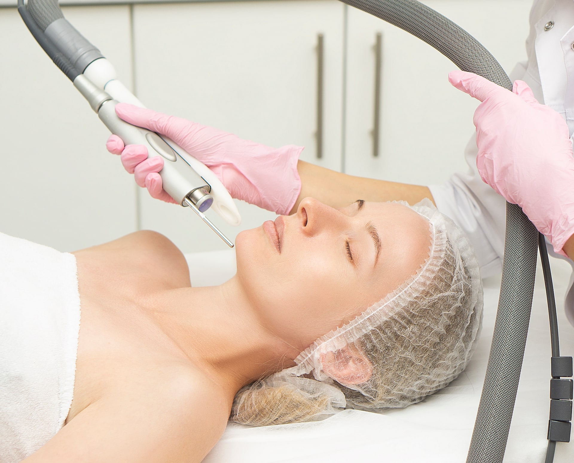 ca97675144e9189caf0720e1ea086309e57a5e00 Clinician performing non-invasive laser facial treatment on patient in medical aesthetic clinic setting