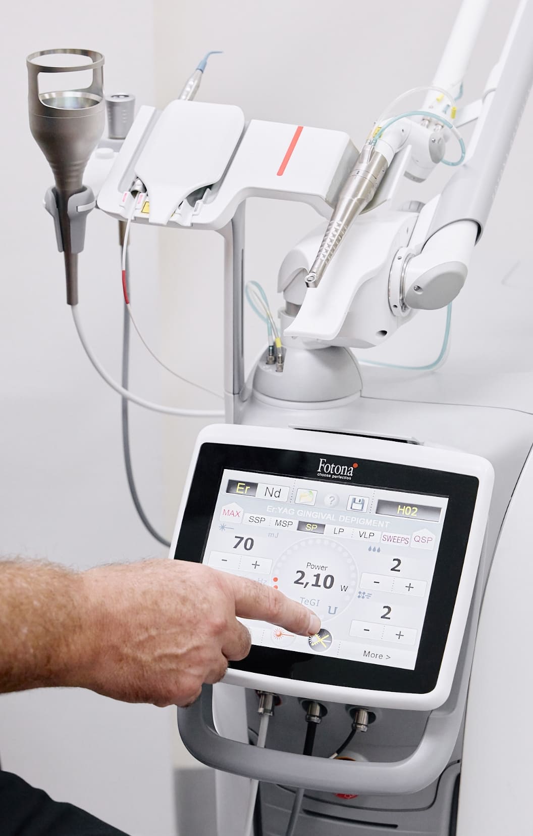 Dentist operating Fotona dental laser machine touchscreen for gingival treatment in modern dental clinic setup