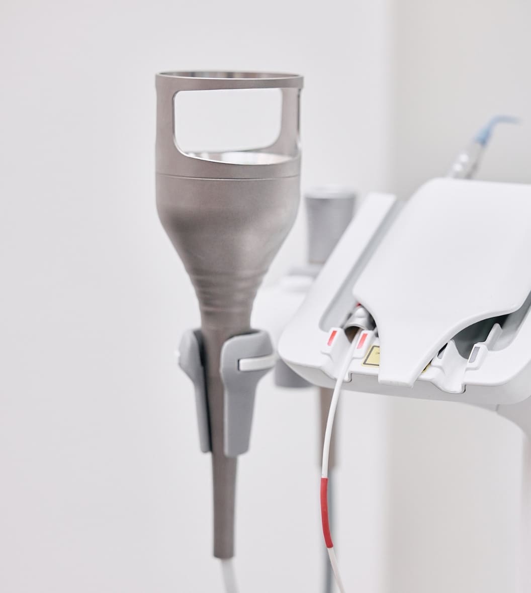 Close-up of dental laser handpiece and medical device attachment mounted on modern dental equipment unit