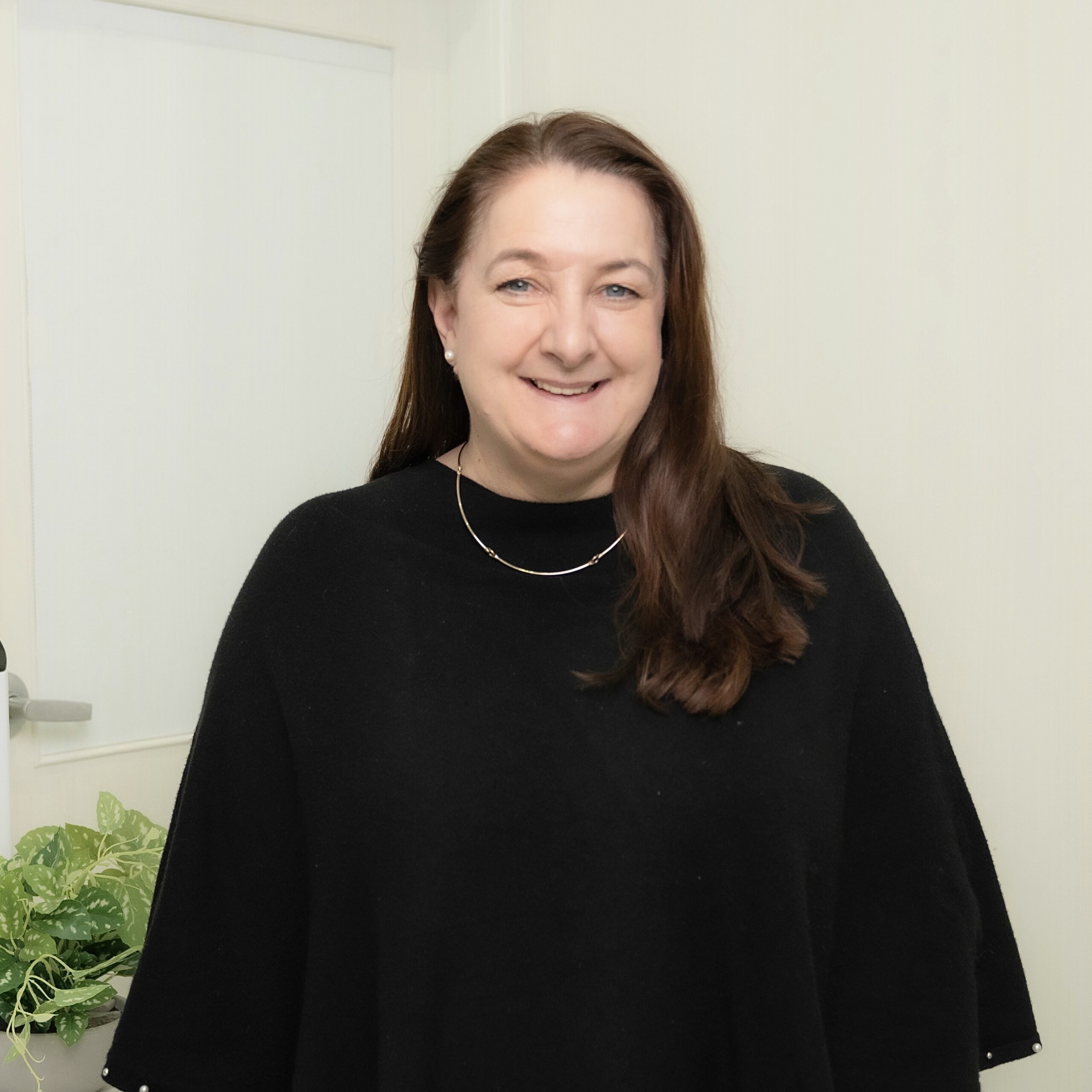 Professional portrait of a smiling woman wearing a black top.
